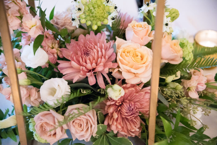 An arrangement of pink and peach flowers on a table.