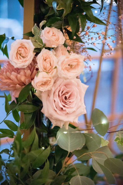 An arrangement of pink roses and greenery in a glass container.