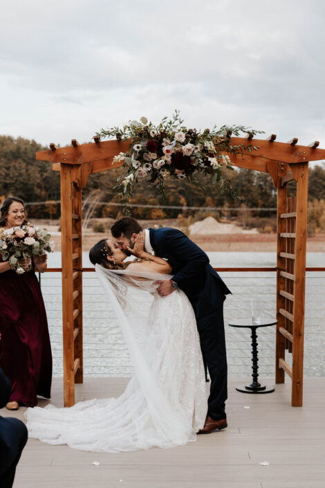 A bride and groom kissing on the deck of a boat.