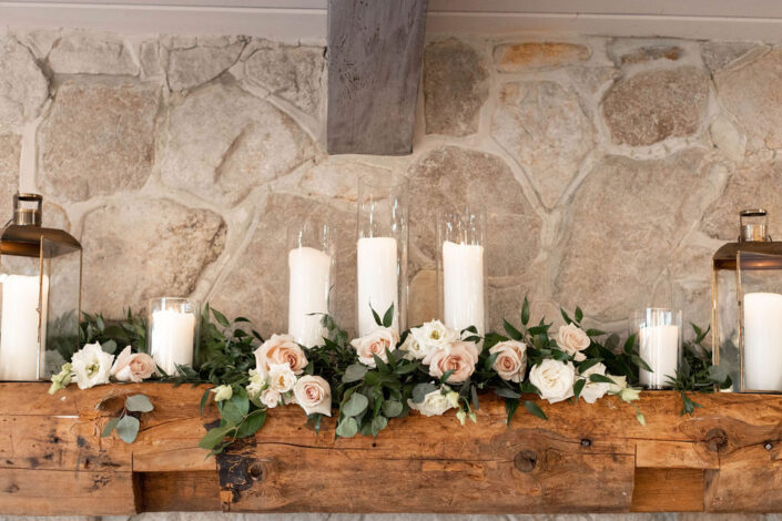 A mantle with candles and flowers on it.