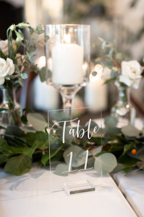 A clear table number with eucalyptus and eucalyptus leaves.