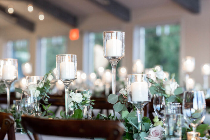 A table with candles and greenery at a wedding reception.
