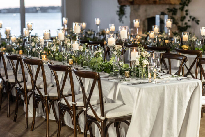 A wedding reception table set up with candles and greenery.