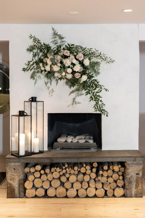 A fireplace with logs and flowers on it.