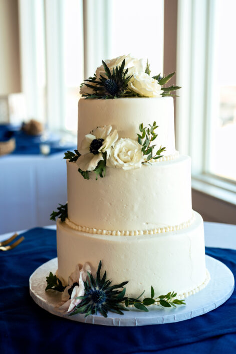 A white wedding cake on a blue tablecloth.