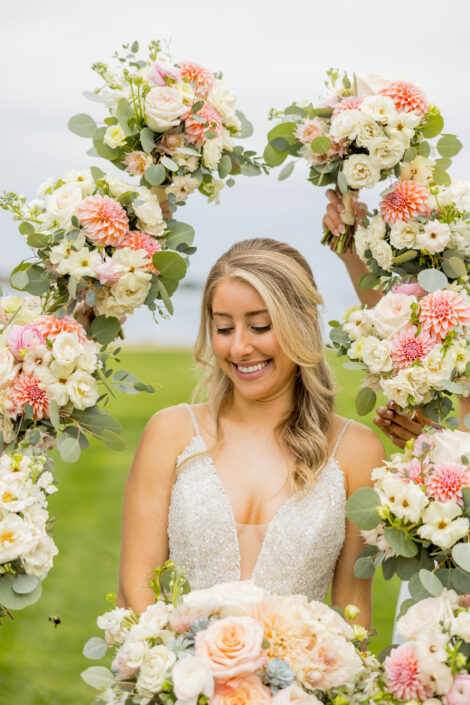 A bride smiles while holding a bouquet of flowers.