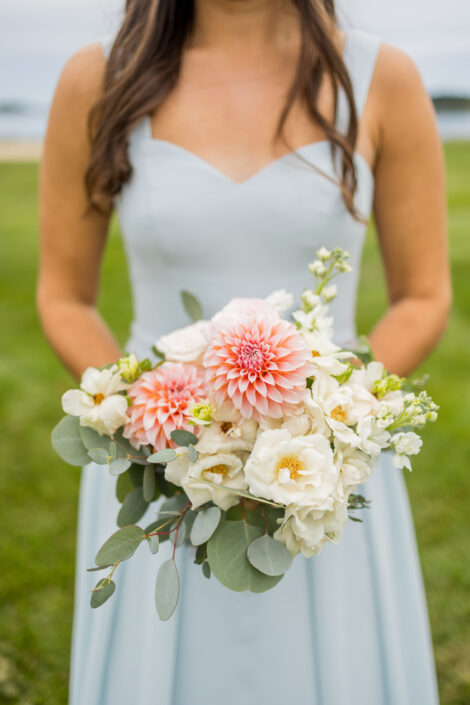 A bridesmaid holding a bouquet of white and pink flowers.