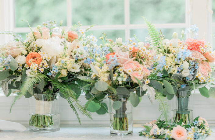 Bridesmaids' bouquets in vases on a window sill.