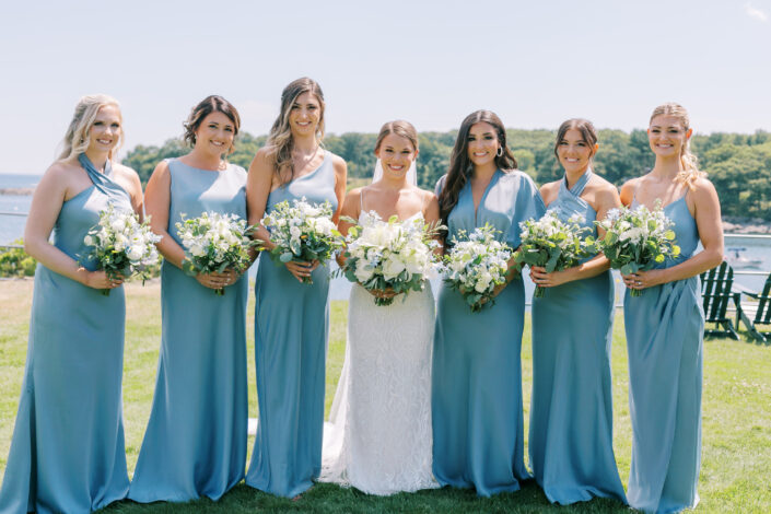 A group of bridesmaids in blue dresses holding bouquets.