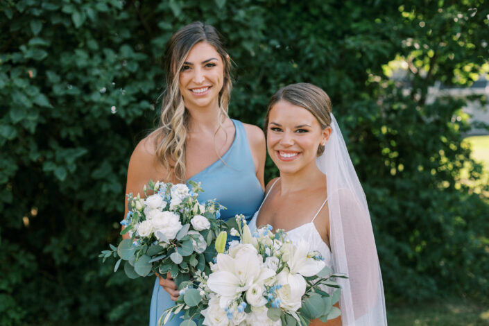 Two bridesmaids in blue dresses holding bouquets.
