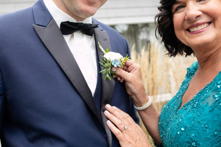 mother putting boutonniere on groom