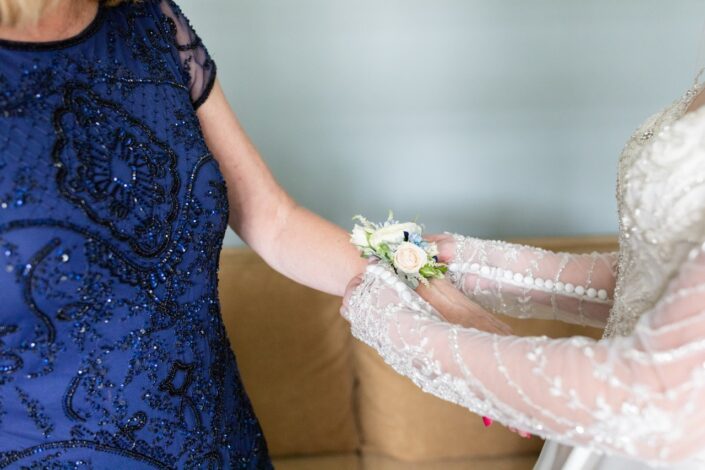 bride putting corsage on mother