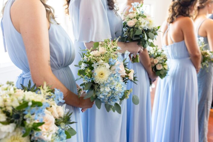 Bridesmaids in blue dresses holding bouquets.