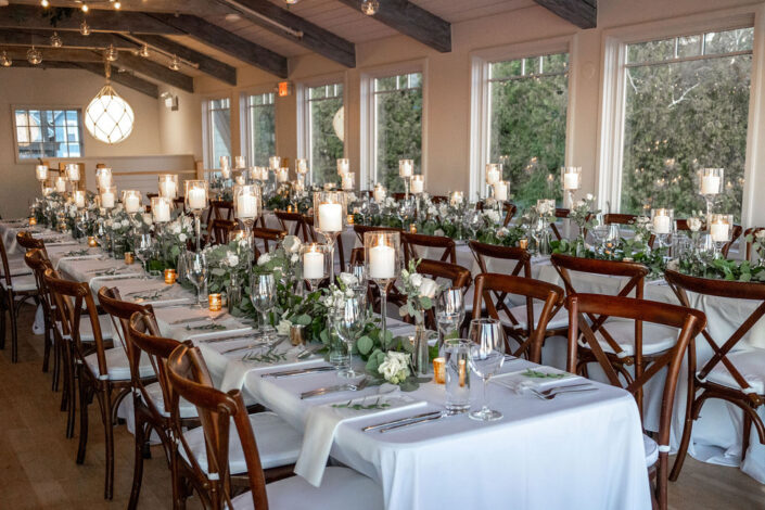 A long table set up with white linens and candles.