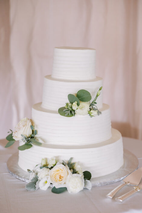 A white wedding cake with white flowers on top.