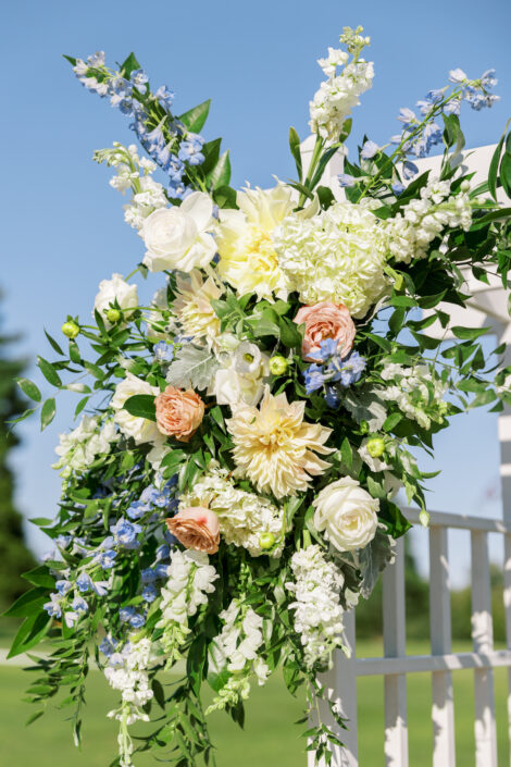 A white wedding arch with blue and white flowers.