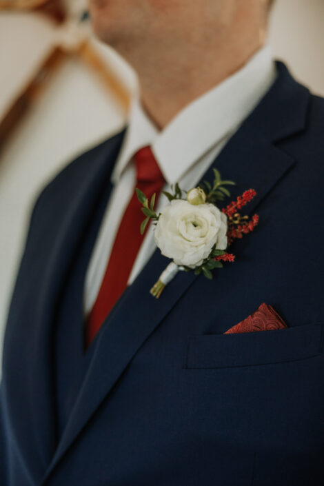 A man in a blue suit with a red flower on his lapel.