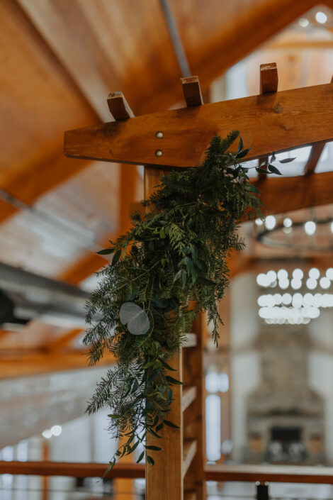 A wooden wedding arch with greenery hanging from it.