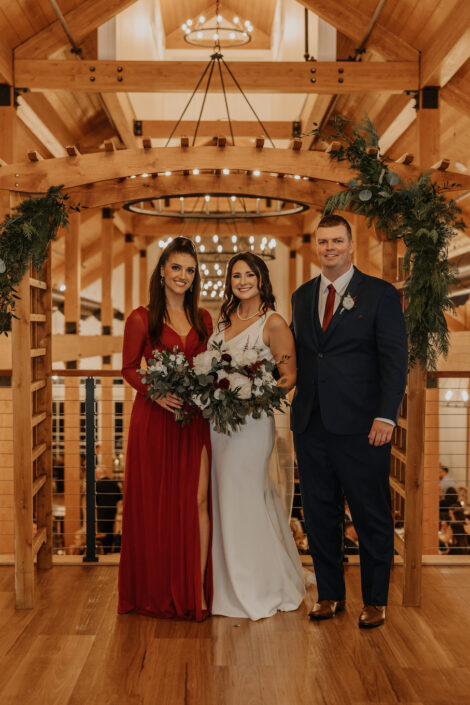A bride and groom posing in front of a wooden barn.