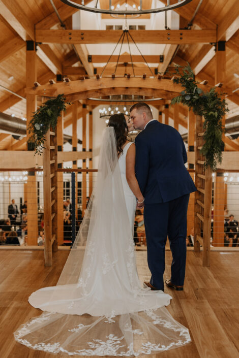 bride and groom kissing in wooden wedding hall