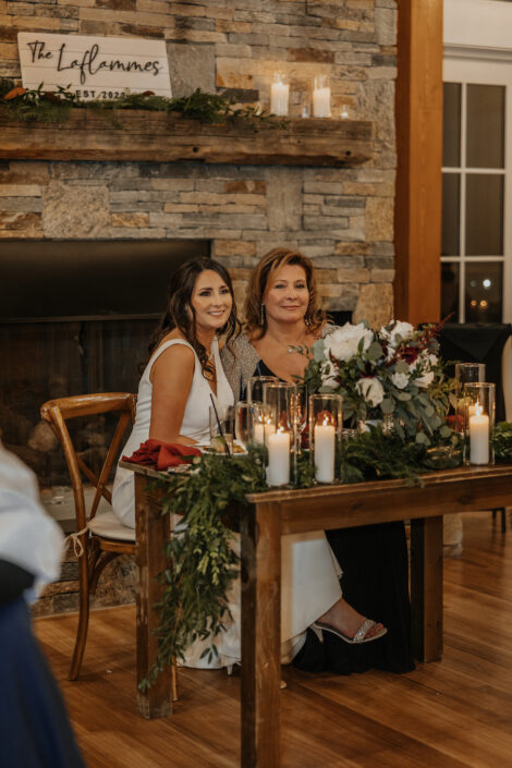bride and mother sitting behind flowers and candles