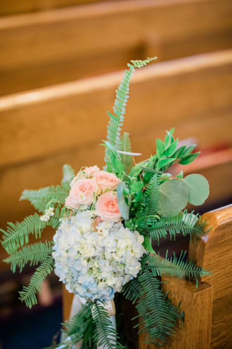 A flower arrangement on the pews of a church.
