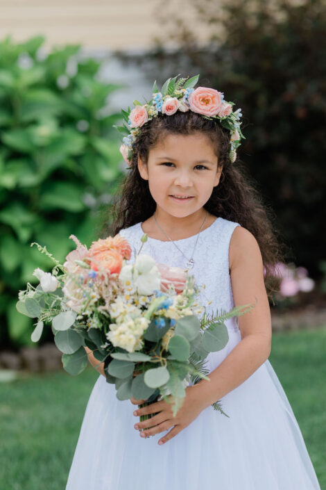 A little girl in a white dress holding a bouquet.